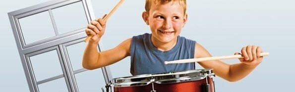 Dobon játszó kisfiú egy műanyag ablakkeret mellett